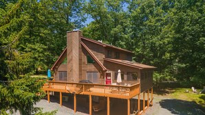 A cabin with a wooden deck, a chimney, and a porch with outdoor seating. - Pocono Chalet- walking distance to Lake Wallenpaupack- 3 Full baths (Lakeville)