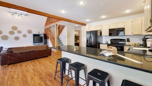 A modern kitchen with a central island, wooden flooring, and a staircase leading to another level. - Pocono Chalet- walking distance to Lake Wallenpaupack- 3 Full baths (Lakeville)