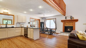 A spacious living area with a fireplace, wooden flooring, and a dining area with a table and chairs. - Pocono Chalet- walking distance to Lake Wallenpaupack- 3 Full baths (Lakeville)