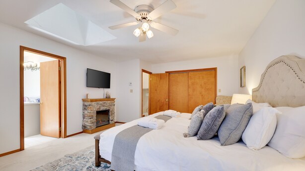 A bedroom with a bed, a ceiling fan, a fireplace, and a TV. - Pocono Chalet- walking distance to Lake Wallenpaupack- 3 Full baths (Lakeville)