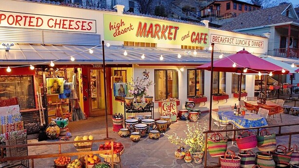 Een markt met verschillende kraampjes waar fruit, groenten en kunsthandwerk verkocht worden.