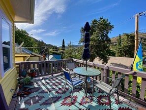 A balcony with a patterned floor, a table, chairs, and a flag.