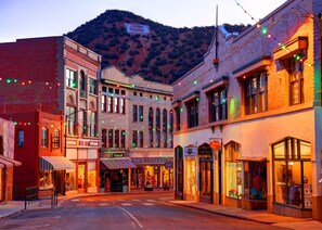 A street view of a town with buildings, shops, and a mountain in the background.