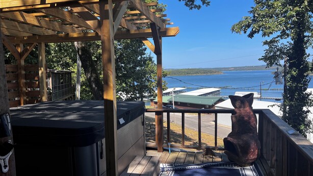 Une terrasse en bois offrant une vue sur un lac et des bâtiments en arrière-plan.