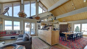 A spacious living area with a large window, a sofa, a dining table, and a kitchen area. - Cora Home w/ Mountain Views - Fishing On-Site! (Cora)