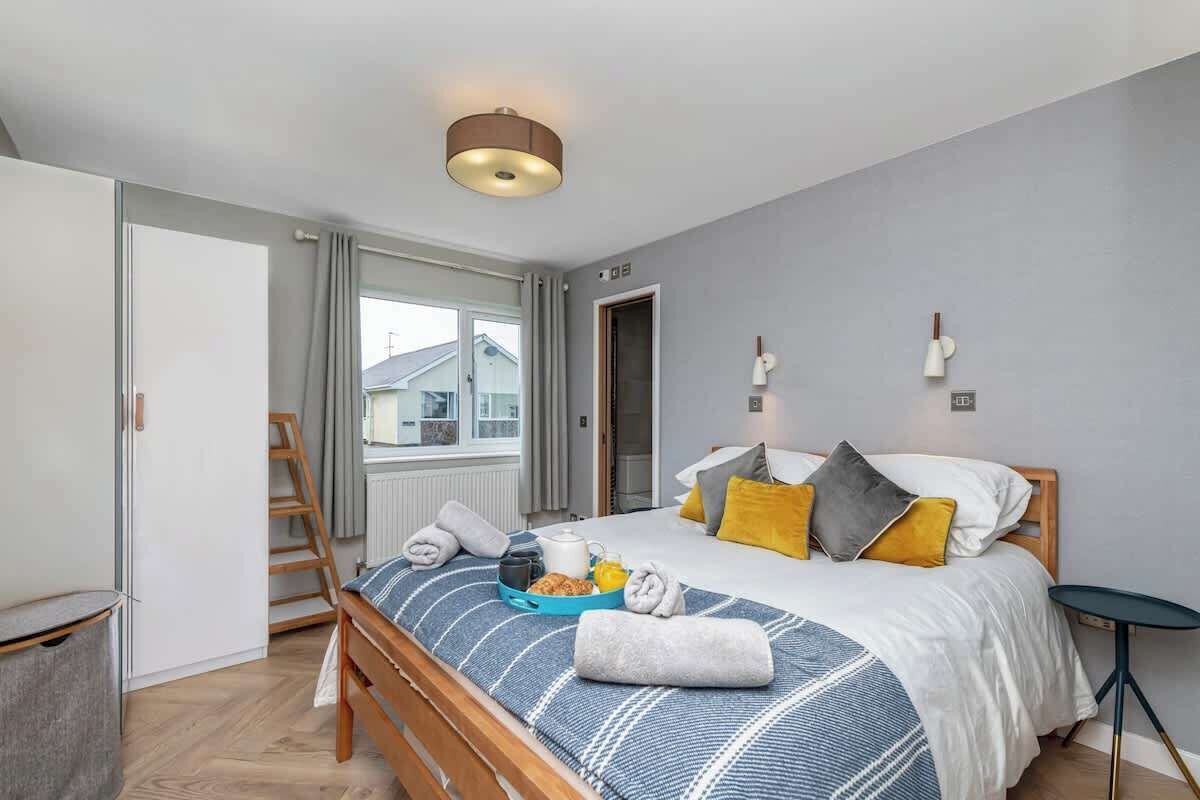 A bedroom with a bed, bedside table, lamp, and a window.