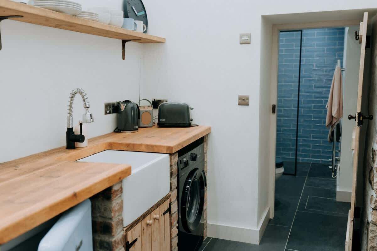 A compact kitchen with a wooden countertop, a washing machine, and a sink.