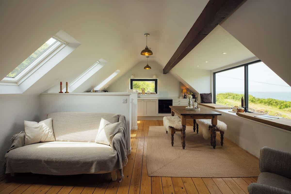 Une chambre confortable aménagée en mezzanine, avec un grand lit, une table à manger et une vue sur l’extérieur.