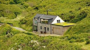 Une maison moderne avec un toit en pente, une façade en pierre et un garage.