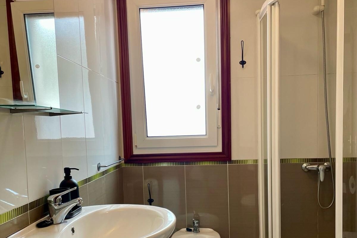 A bathroom with a sink, bidet, toilet, and a glass-enclosed shower.