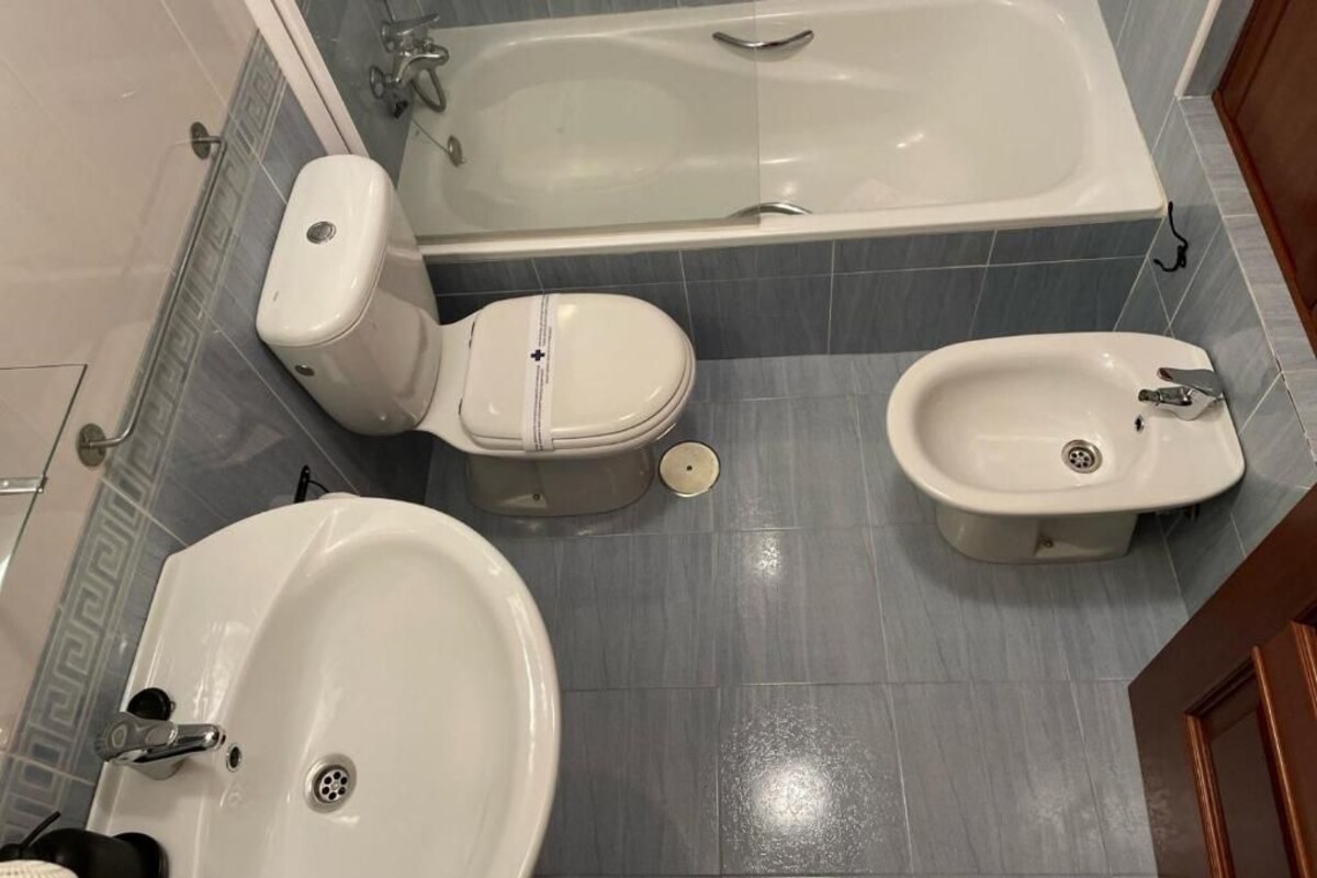 Een badkamer met een bad, toilet en douchetoilet.