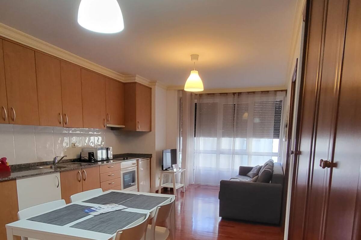 Un apartamento pequeño con comedor, kitchenette y sala de estar con sofá.