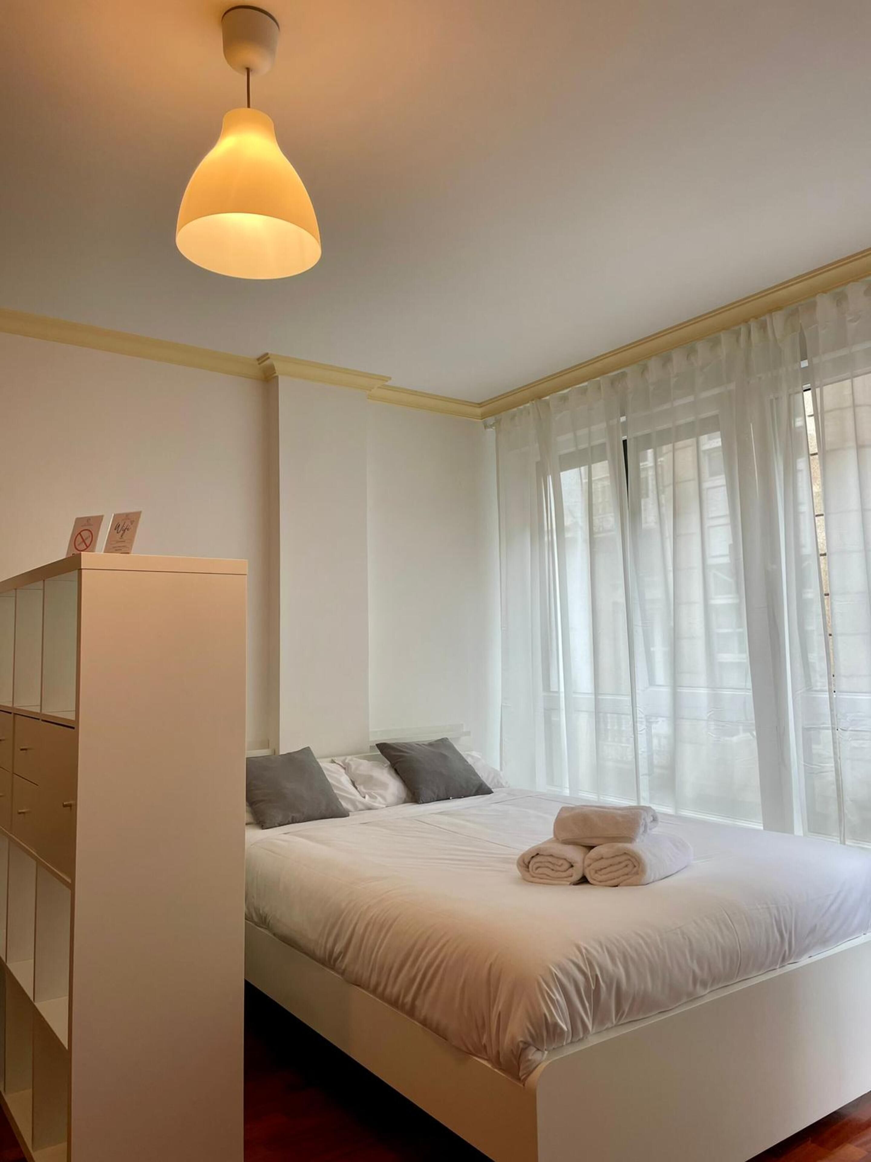 A bedroom with a bed, a wardrobe, and a hanging light fixture.