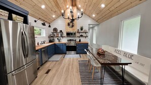 Una cocina moderna con un refrigerador de acero inoxidable, armarios azules, una isla central y un candelabro.