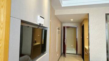 Pasillo de hotel con un muro espejado, una zona de recepción y una puerta que da a otra habitación.