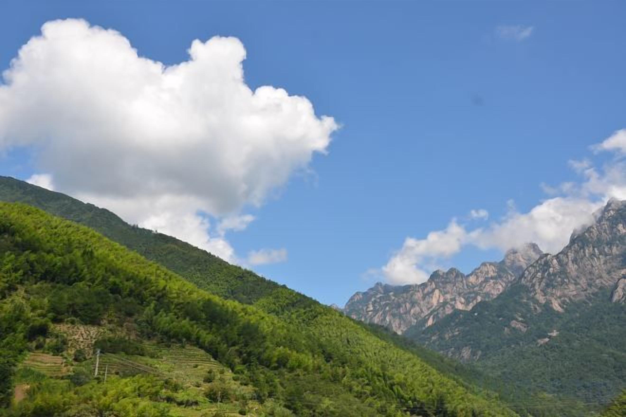 Paisagem montanhosa com céu claro e uma grande nuvem.