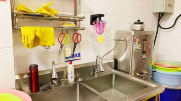 A kitchen with stainless steel sinks, a dish rack, and various kitchen utensils.