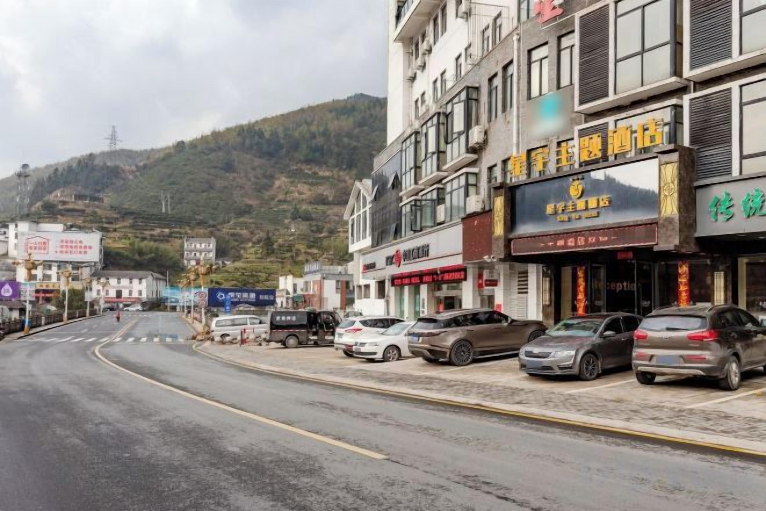 A street with parked cars and buildings with signage.