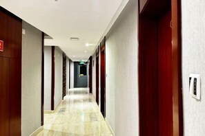 A hotel hallway with wooden doors, a tiled floor, and a light-colored wall. - Xingyu Theme Hotel (Huangshan Scenic Area) (Huangshan City)