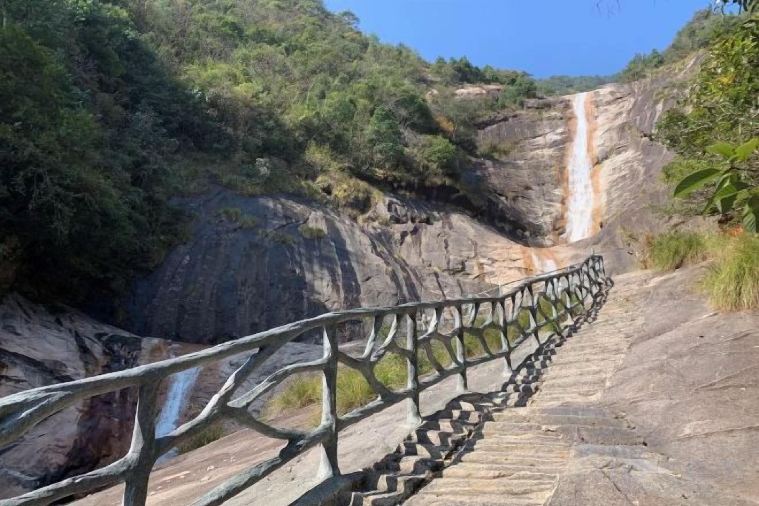 A staircase leading to a waterfall with a stone railing.