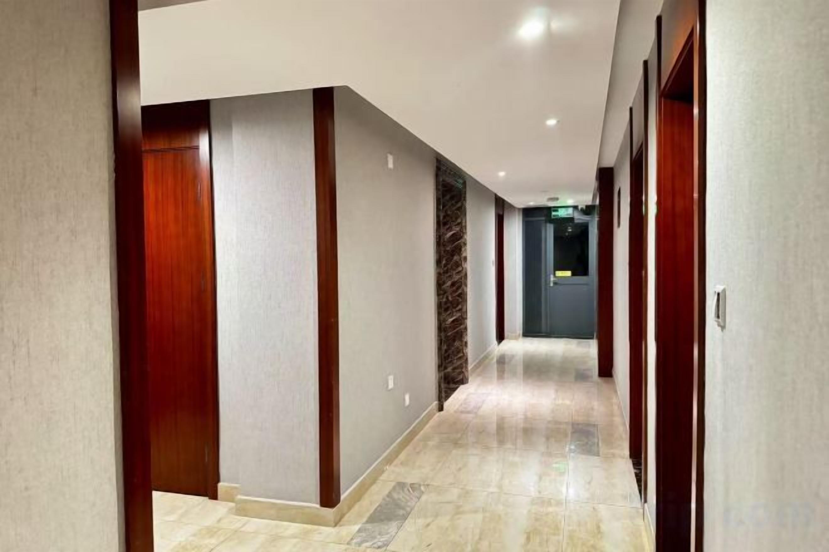 A corridor with wooden doors and a marble floor.