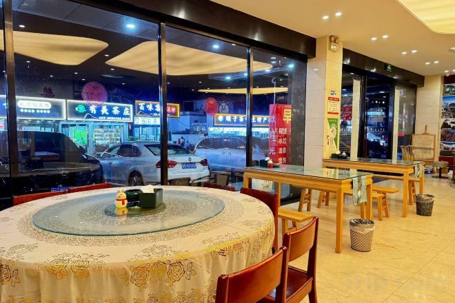 An indoor dining area with round tables and chairs, a view of the street outside, and a trash can.