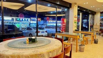 An indoor dining area with round tables and chairs, a view of the street outside, and a trash can.