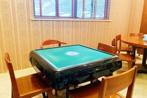 A pool table with four chairs, a window with blinds, and a patterned wall. - Xingyu Theme Hotel (Huangshan Scenic Area) (Huangshan City)