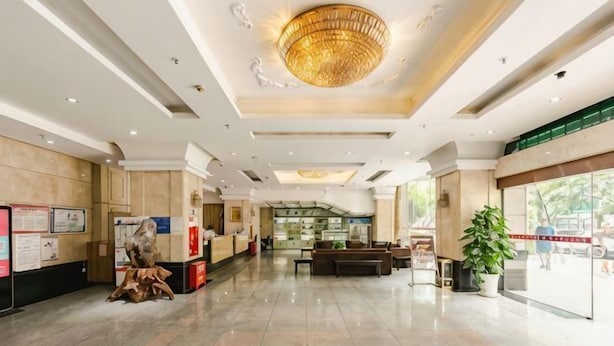 Un hall espacioso con candelabro, mostrador de recepción, zona de estar y un amplio ventanal.