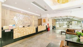 A hotel lobby with a reception desk, a map on the wall, a seating area, and a display of items.