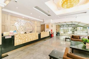 Un vestíbulo de hotel con una mesa de recepción, un mapa en la pared, un área de descanso y una exhibición de objetos.