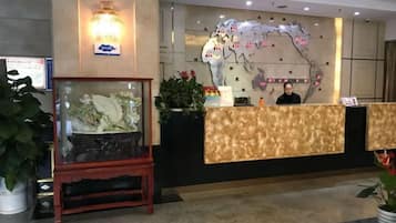 A hotel reception area with a reception desk, a glass display case, and a wall-mounted map.