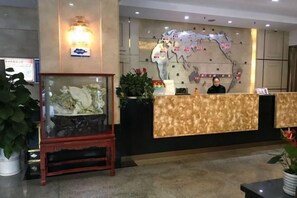 A hotel reception area with a reception desk, a glass display case, and a wall-mounted map. - Hengli Hotel (Panzhihua)