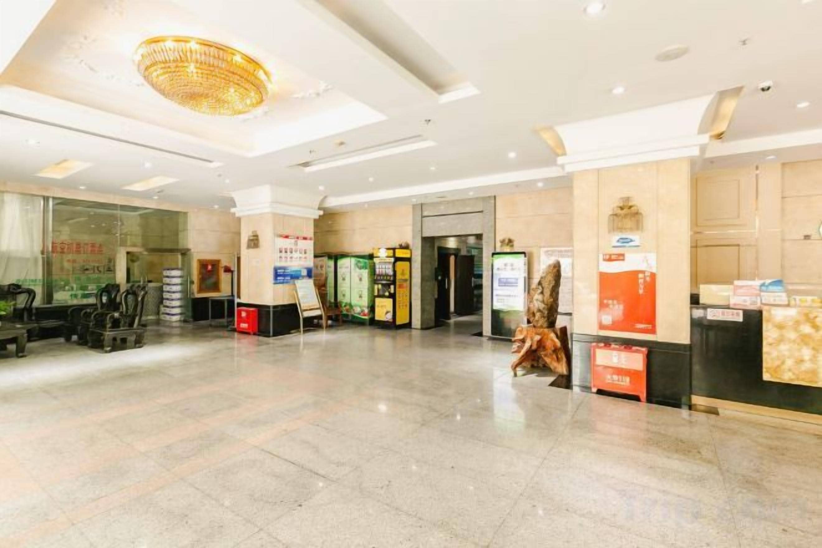 A spacious lobby with a chandelier, a reception desk, vending machines, and a staircase.