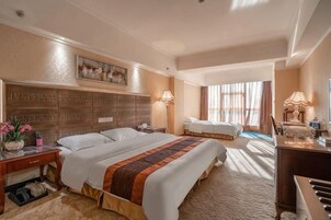 Habitación de hotel con una cama grande, un escritorio con lámpara, una silla, un piano y vistas al exterior.