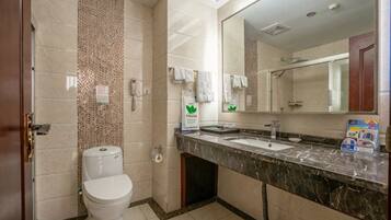 A bathroom with a toilet, sink, mirror, and tiled walls.