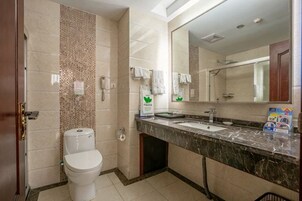 Un baño con inodoro, lavamanos, espejo y paredes de azulejos.