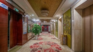 Un pasillo de hotel con alfombra estampada, paredes de madera y un candelabro.