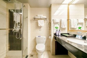 A bathroom with a glass-enclosed shower, a toilet, a sink, and a mirror. - Hengli Hotel (Panzhihua)