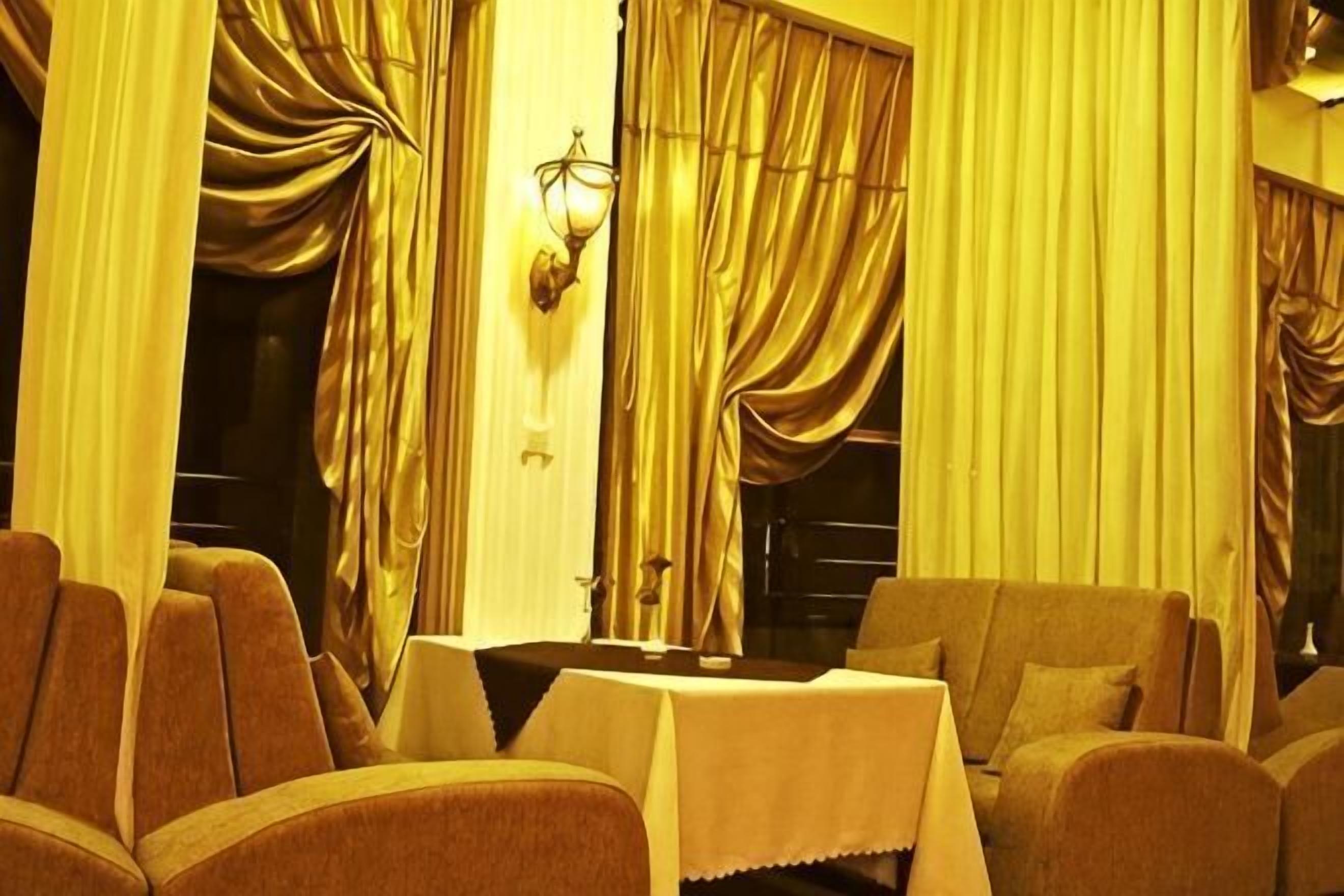 A room with a table, chairs, and curtains.