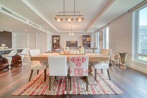 Une cuisine moderne avec un îlot central en bois, des chaises blanches et une grande fenêtre.