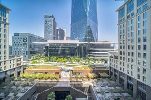 Un complexe immobilier urbain moderne composé de plusieurs immeubles de grande hauteur, d’une cour centrale agrémentée de verdure et d’une combinaison de façades en verre et en béton.