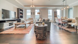 Ein geräumiges Wohnzimmer mit einem großen Flachbildfernseher, einem Couchtisch, einer Couch und einem Essbereich mit Stühlen und einem Tisch.