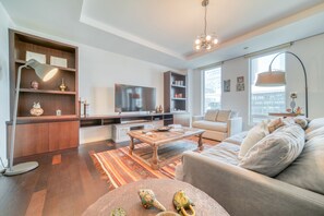 A modern living room with a sofa, coffee table, TV, and bookshelves.