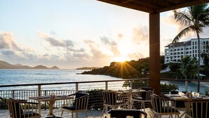 A seaside restaurant with outdoor seating, overlooking the ocean and a distant mountain range. - Secure Booking Beachfront Ritz 3 Bedroom Property Concierge Services Included (St Thomas)