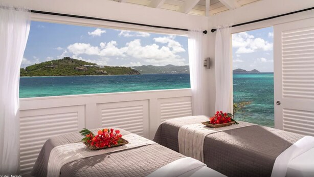 A room with two beds, a window with a view of a tropical island and turquoise waters. - Secure Booking Beachfront Ritz 3 Bedroom Property Concierge Services Included (St Thomas)