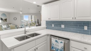 A modern kitchen with white cabinetry, a stainless steel sink, and a dishwasher.