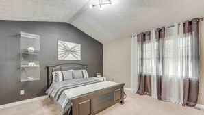 Une chambre à coucher comprenant un lit, une table de chevet, une étagère fixée au mur et un luminaire au plafond.
