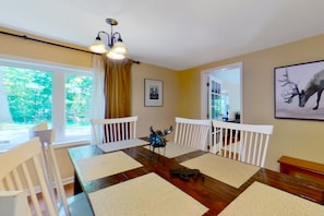 A dining area with a wooden table, white chairs, and a chandelier.