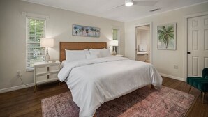 Ein Schlafzimmer mit einem Bett, Nachttischen, einem Deckenventilator und Kunstwerken an den Wänden.